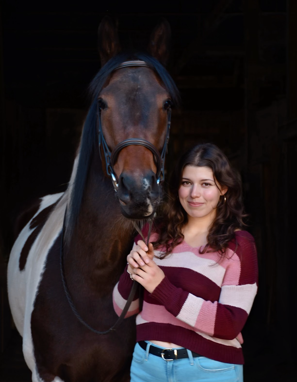 Woman standing next to a horse with a dark background
